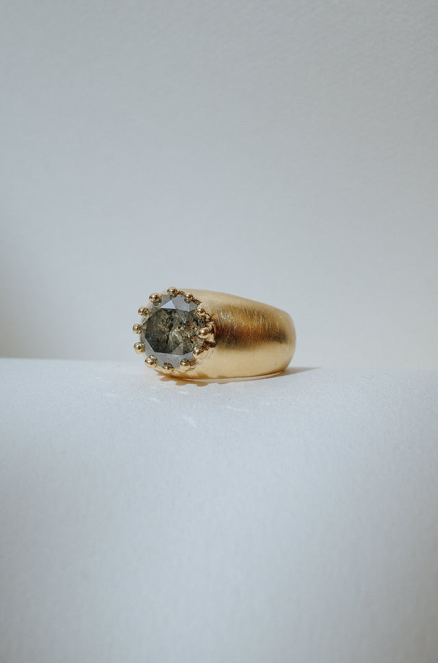 Large round speckled grey diamond surrounded by 18 karat gold beads. On a wide and chunky etched texture cigar band.