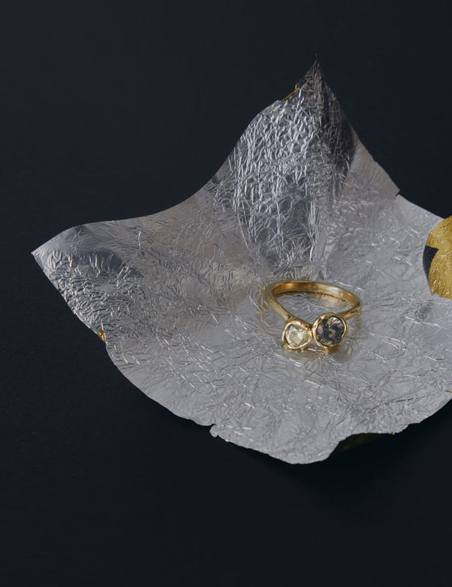 Gold ring with two champagne sapphire gemstones on a textured silver leaf against a black background